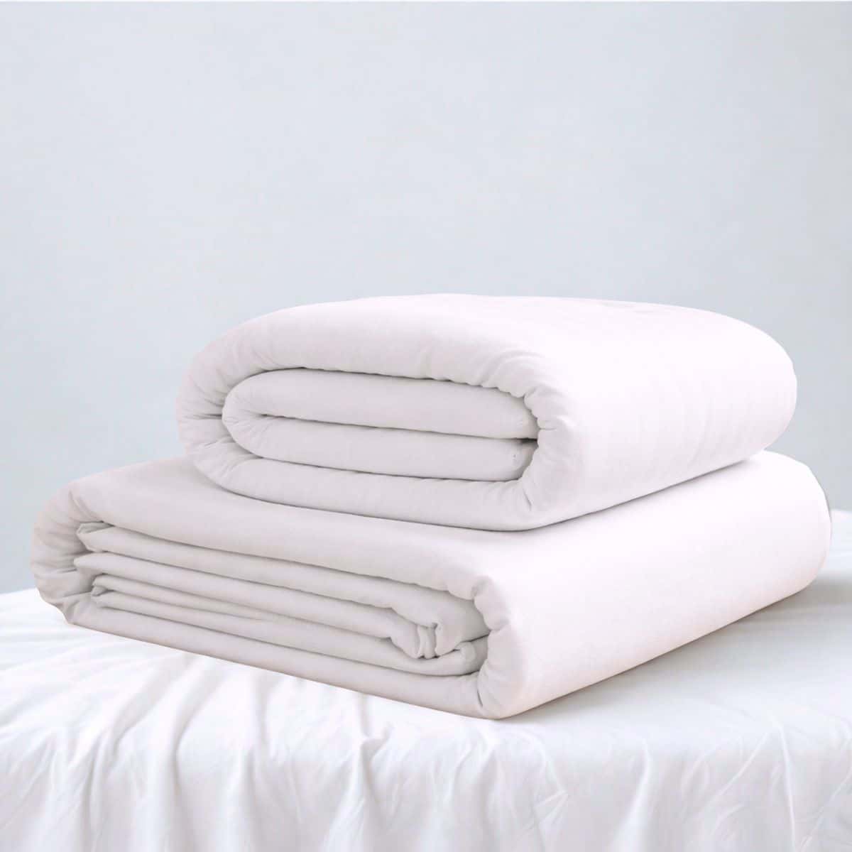 Le drap housse et alèse sont blancs, ils sont pliés l'un sur l'autre et posé sur un support recouvert d'un tissu blanc